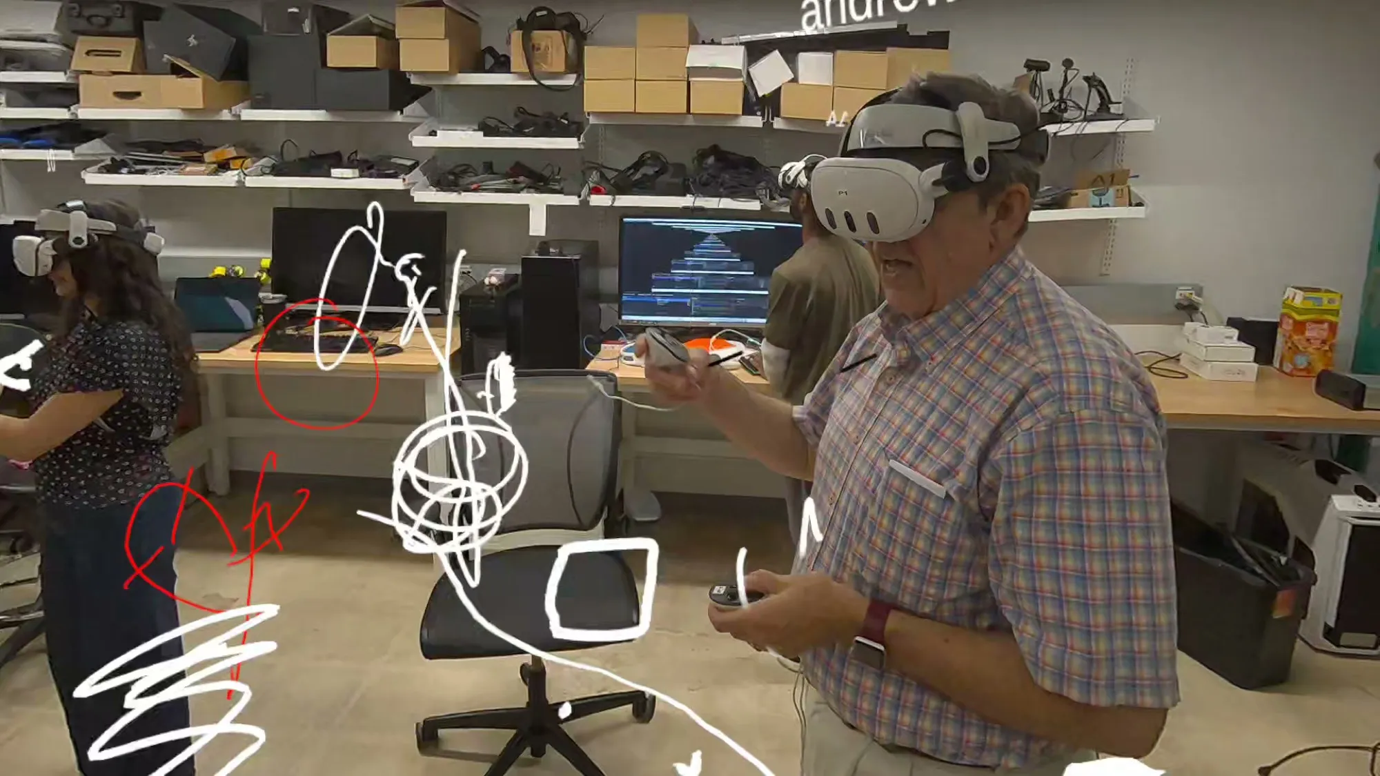 Two people wearing Quest headsets draw white 3D strokes in the air of the lab.