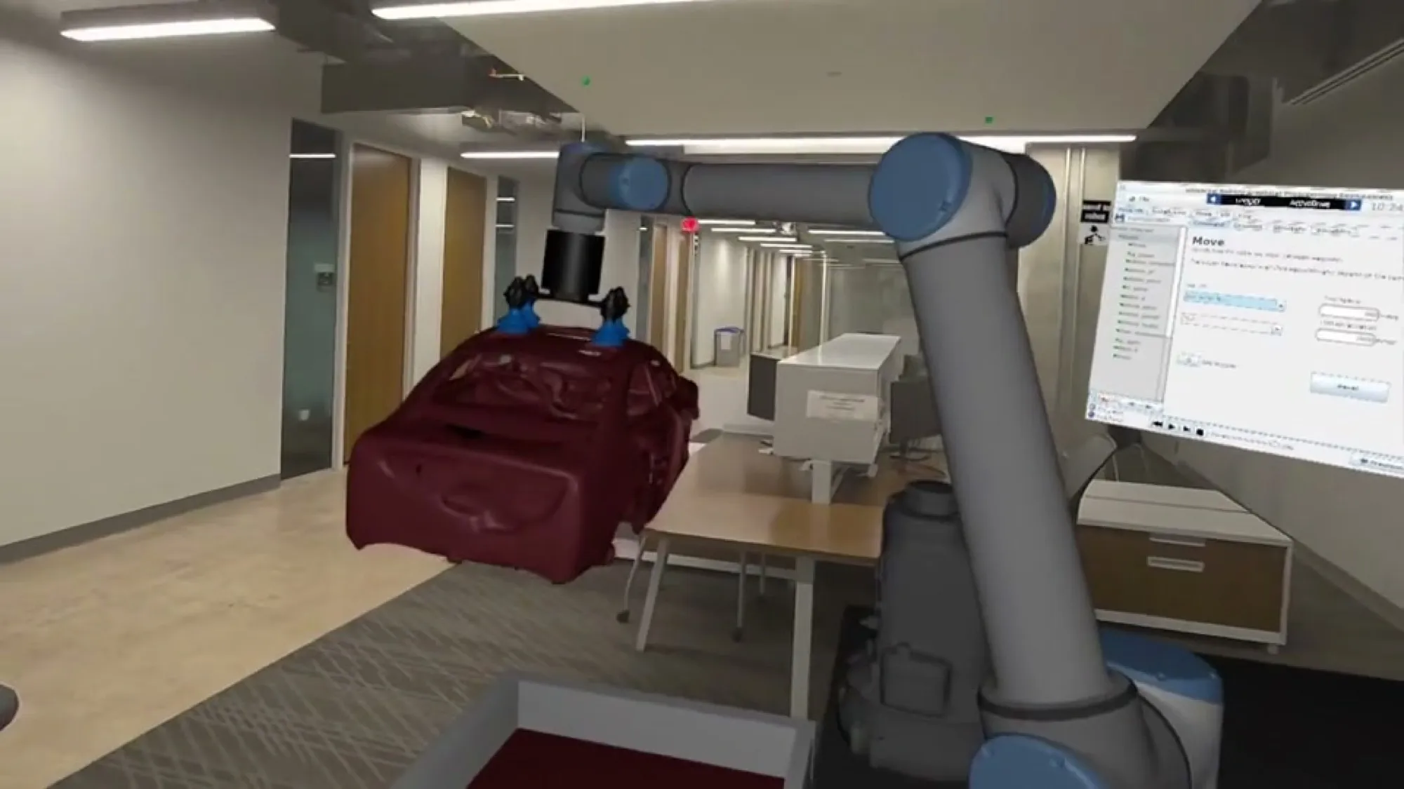 A UR10 collaborative robot arm in the lab holding a virtual car body, seen through a mixed reality headset.